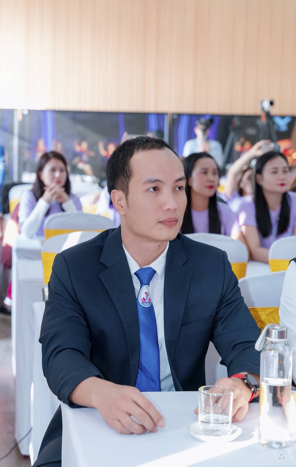 Nguyễn Bảo Bằng mặc vest ngồi dự một chương trình của Liên đoàn Cử tạ, Thể dục, Thể hình tỉnh Nghệ An