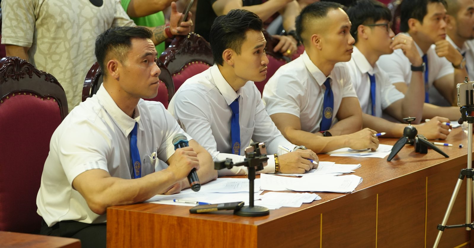 Hàng trọng tài mặc đồng phục sơ mi trắng, cà vạt xanh có huy hiệu Liên đoàn tại Giải vô địch Thể dục Thể hình – Fitness CLB TP Vinh mở rộng 2024