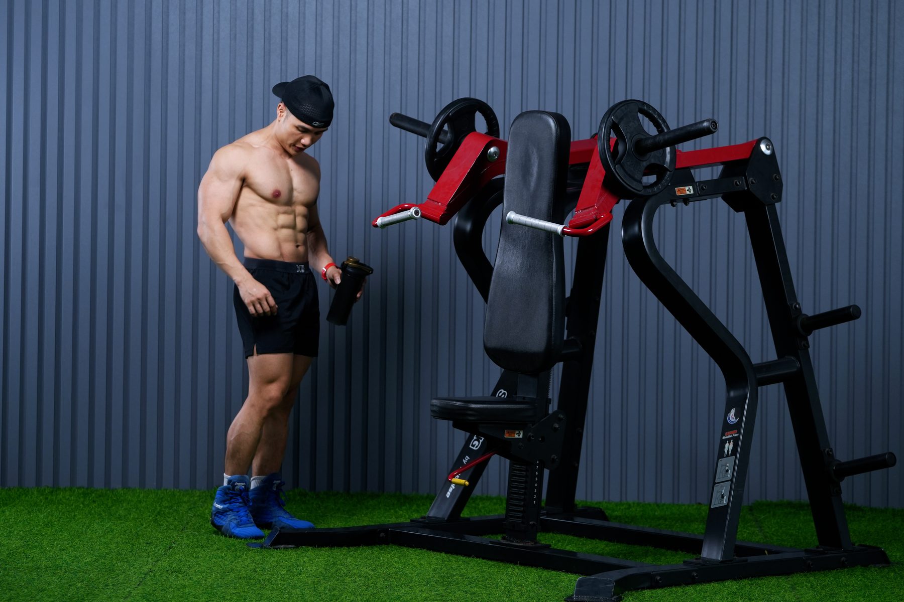 Nguyễn Bảo Bằng cầm bình lắc đứng cạnh máy tập trong phòng gym