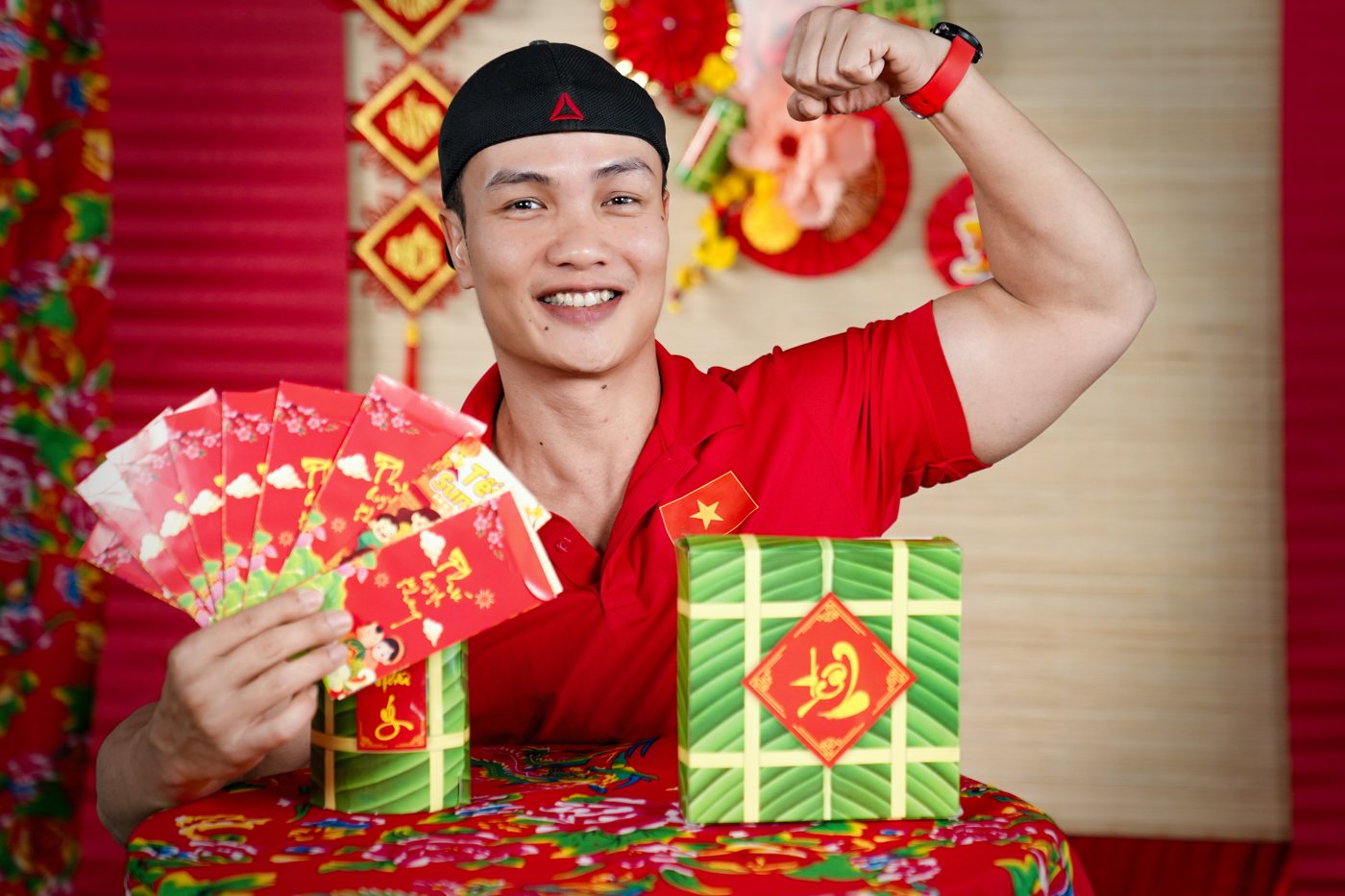 Nguyễn Bảo Bằng gồng cơ tay bên cạnh bánh chưng và phong bao lì xì trên phông trang trí Tết