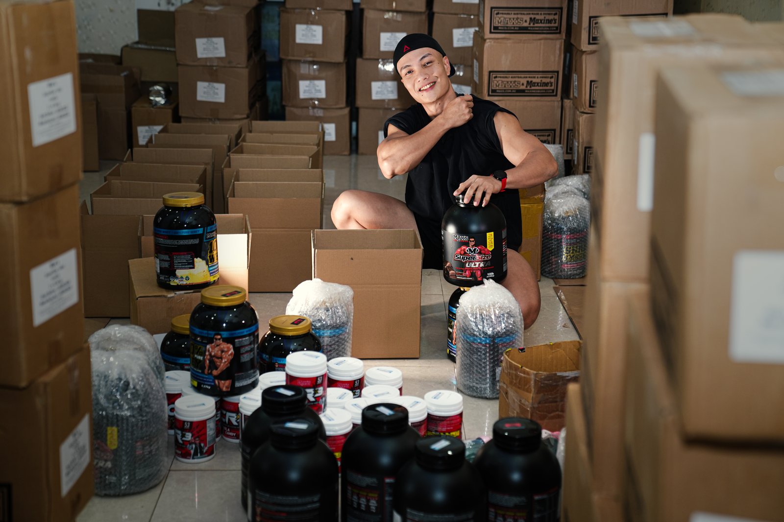 Nguyễn Bảo Bằng đặt tay lên hũ whey protein trong kho hàng thực phẩm bổ sung