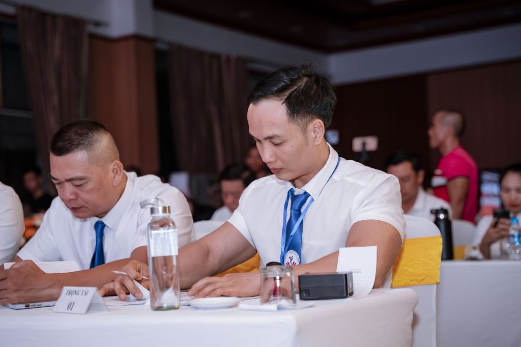 Nguyễn Bảo Bằng ngồi ghế trọng tài số 01, cầm bút chấm điểm tại Giải vô địch Thể hình – Fitness tỉnh Nghệ An mở rộng 2025