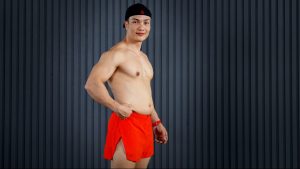 Huấn luyện viên Nguyễn Bảo Bằng đứng nghiêng, tay véo lớp mỡ dưới da vùng bụng