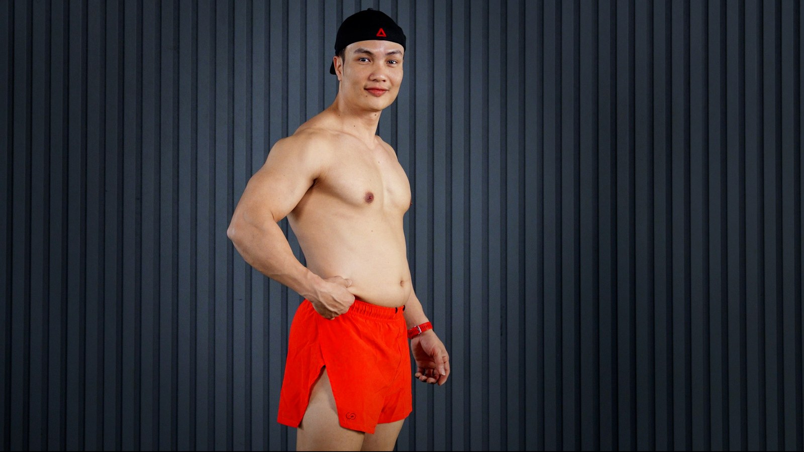 Huấn luyện viên Nguyễn Bảo Bằng đứng nghiêng, tay véo lớp mỡ dưới da vùng bụng