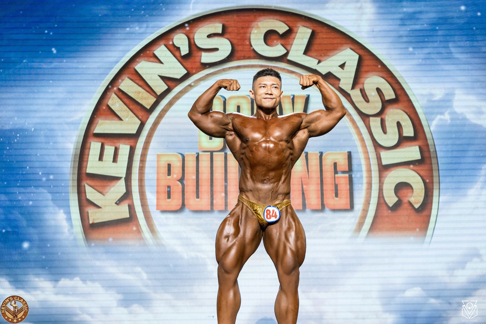 Vận động viên Bodybuilding gồng hai tay trước, cơ bắp to và căng