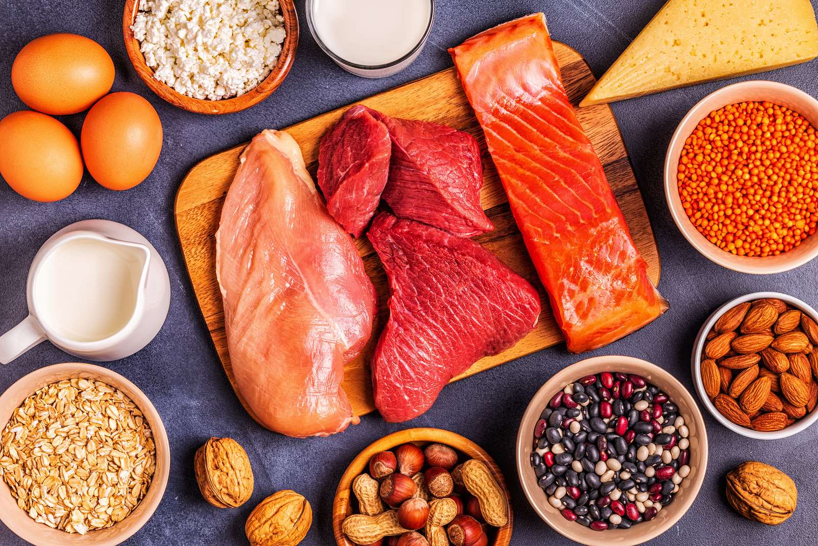Thịt bò, ức gà, cá hồi, trứng, sữa, đậu lăng và các loại hạt bày trên mặt bàn