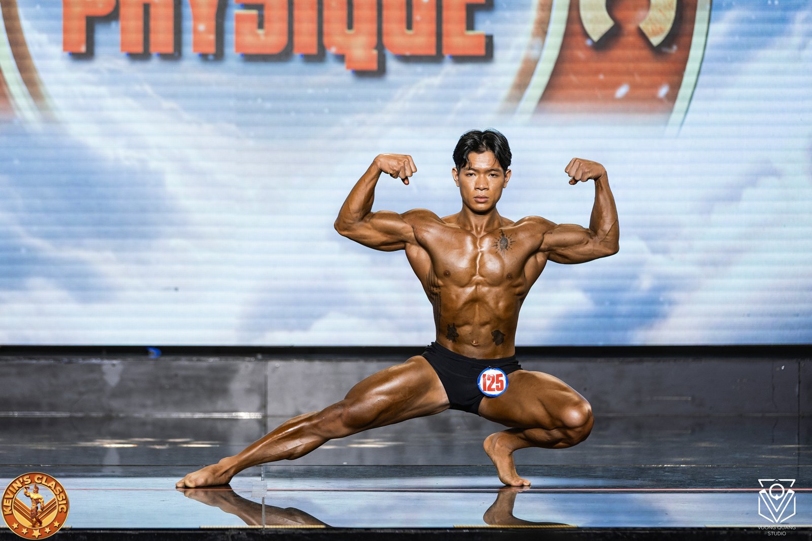 Vận động viên Classic Physique gồng hai tay trước trong tư thế tấn thấp