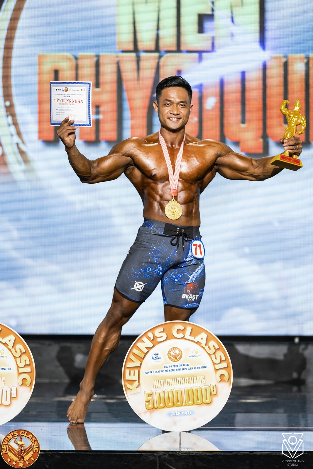 Nhà vô địch hạng Men Physique cầm cúp, giấy chứng nhận, đeo huy chương vàng