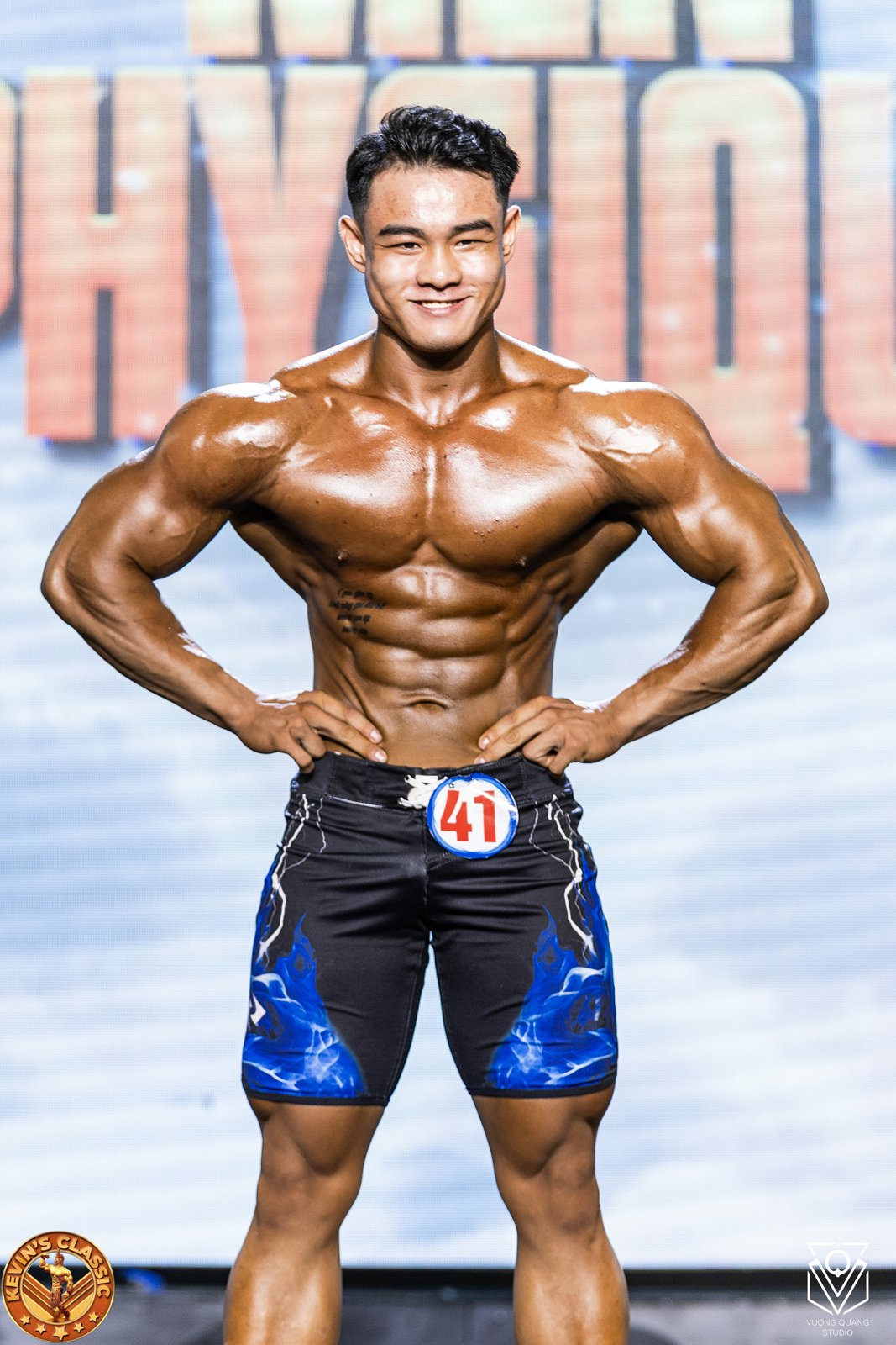 Vận động viên Men Physique mặc quần short dài, vai rộng, eo nhỏ, cơ bụng nét
