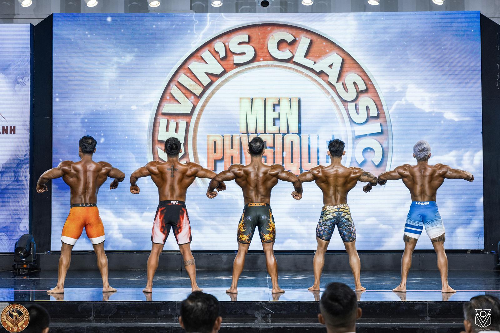 Năm vận động viên Men Physique quay lưng trước phông chữ Men Physique