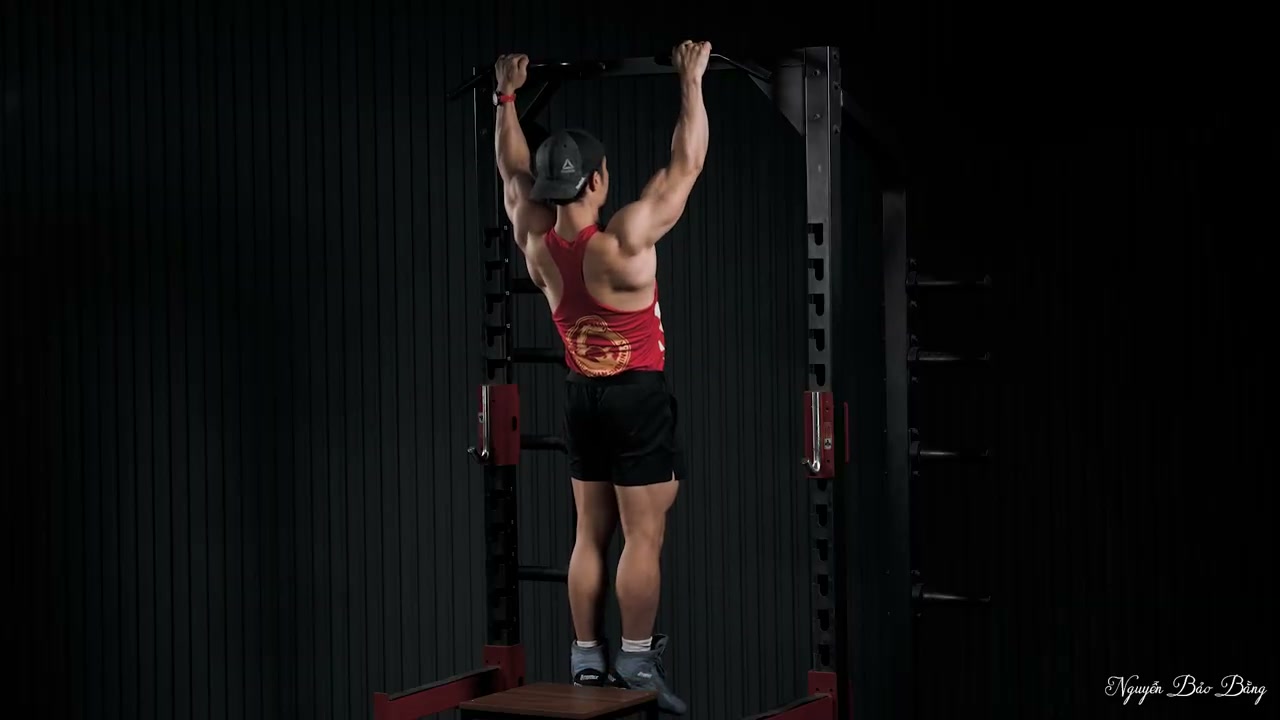 Nguyễn Bảo Bằng treo trên xà, hai tay duỗi hết, nhìn từ phía sau