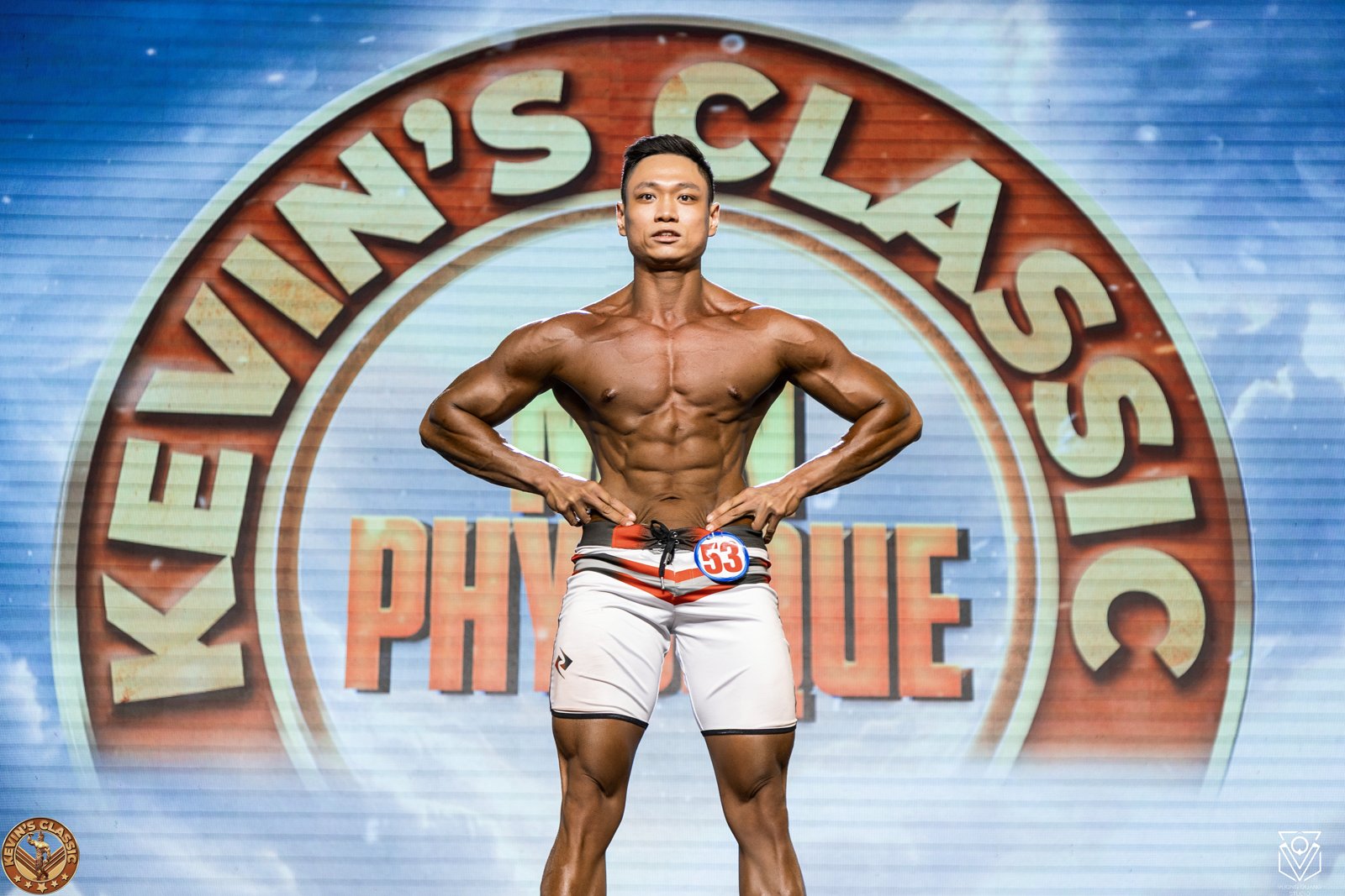 Vận động viên Men Physique chống hông tạo dáng trên sân khấu Kevin's Classic