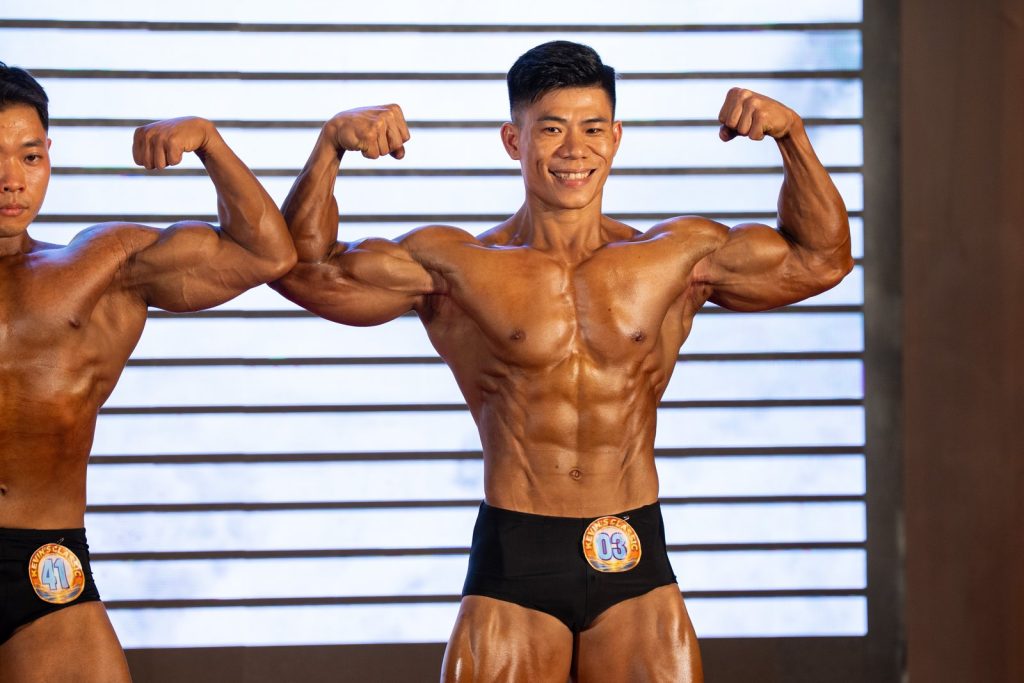 Một vận động viên Athletic Physique nam gồng hai tay trước tại Kevin's Classic lần 5