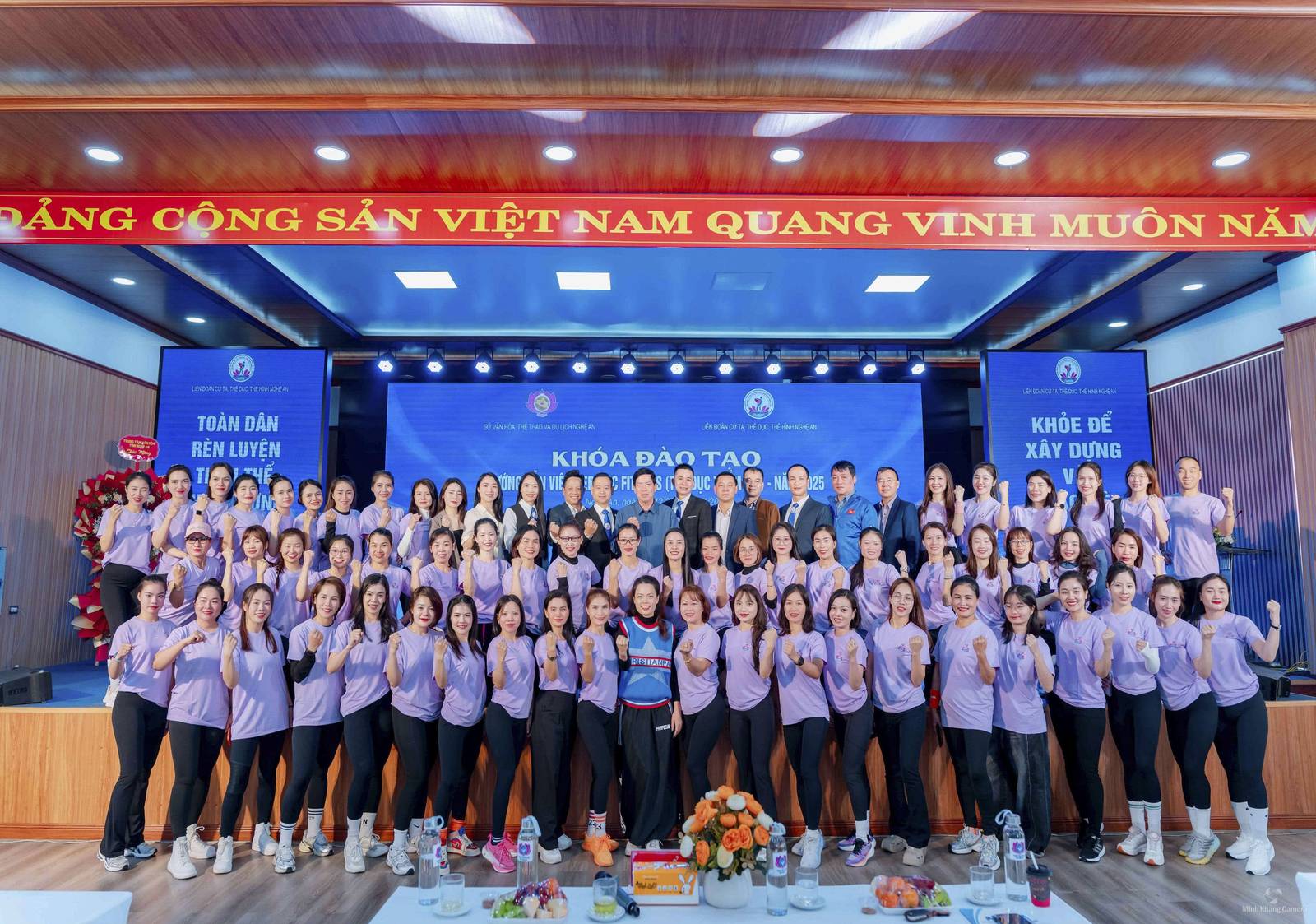 Đông đảo học viên chụp ảnh tập thể trên sân khấu một khóa đào tạo hướng dẫn viên Fitness năm 2025