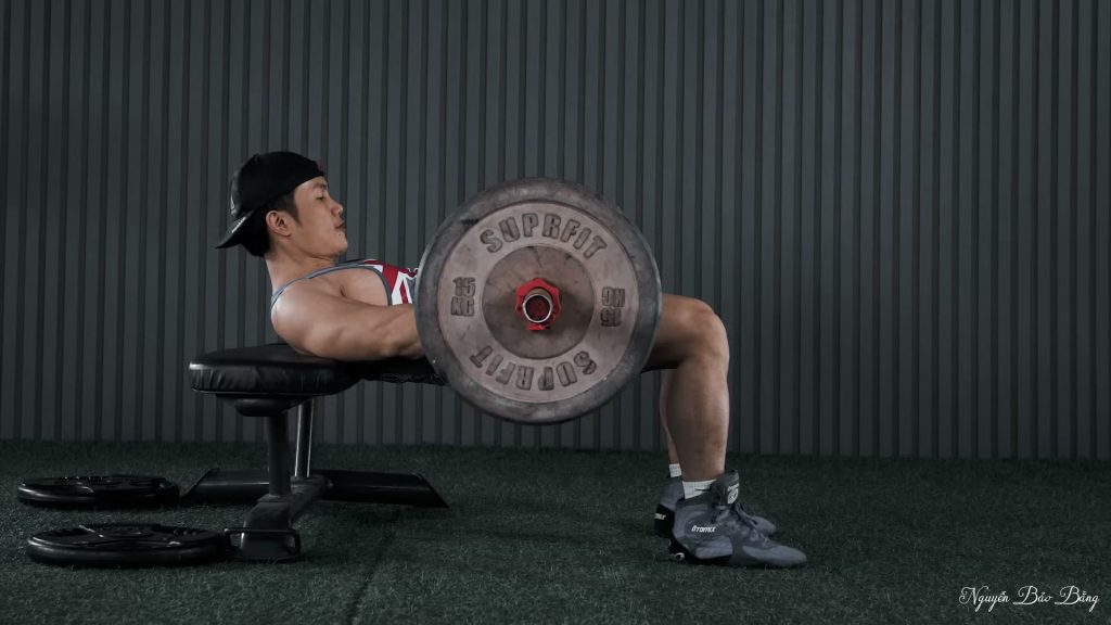 Đẩy hông với thanh đòn, lưng trên tựa mép ghế, nhìn nghiêng