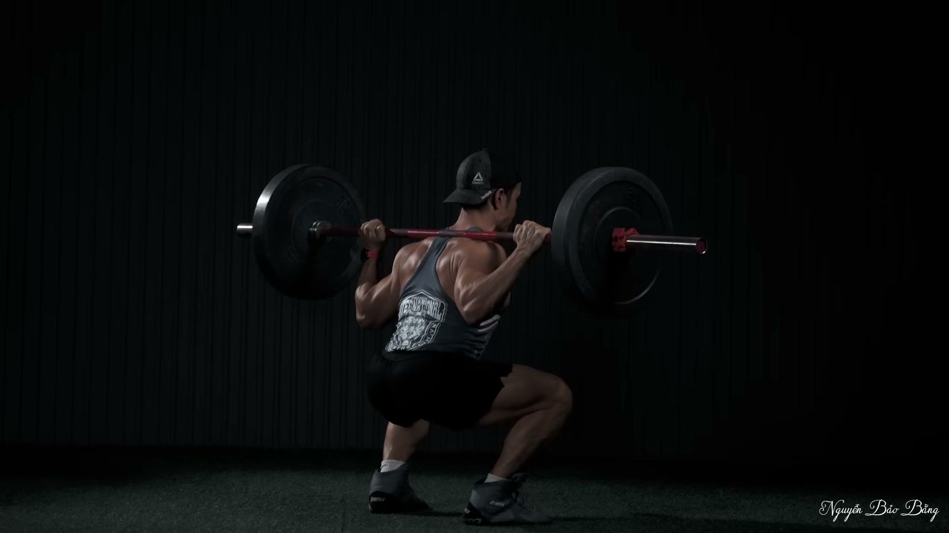 Squat gánh ở đáy động tác, nhìn từ phía trước, thanh đòn có đĩa tạ
