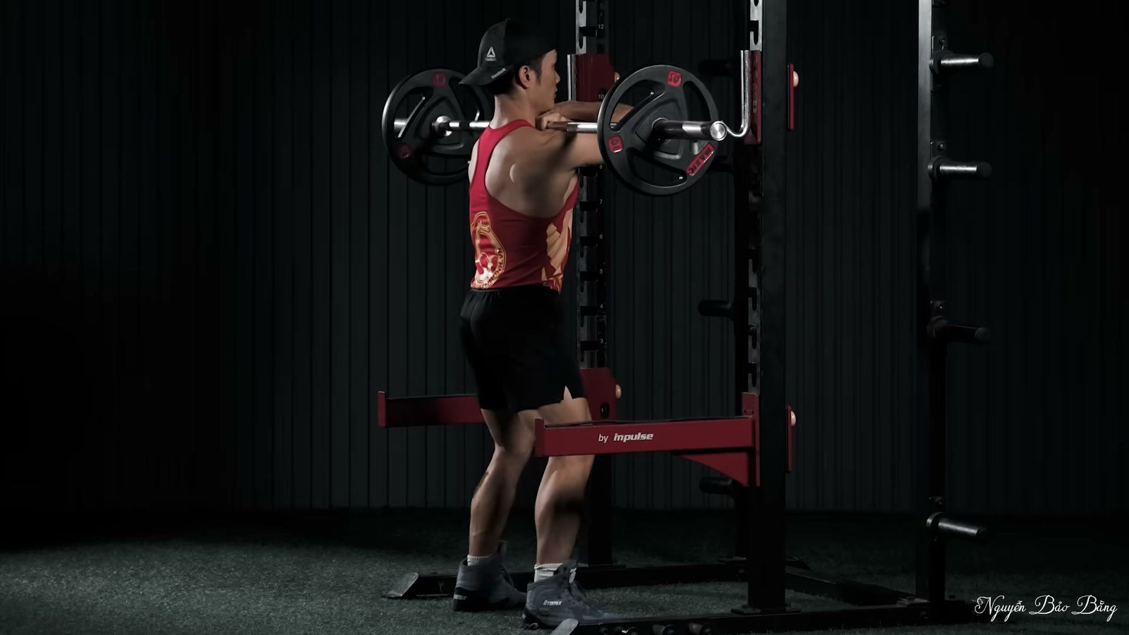 Nguyễn Bảo Bằng squat gánh với thanh đòn trong khung tạ tại phòng tập