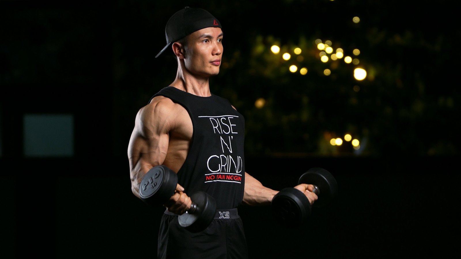 Nguyễn Bảo Bằng cuốn tạ đơn, mặc áo in chữ Rise N Grind trong phòng tập tối