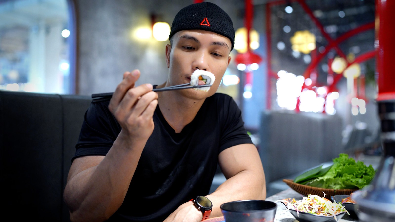 Nguyễn Bảo Bằng cầm đũa gắp một miếng ăn trong bữa ăn tại quán, trên bàn có rau xanh