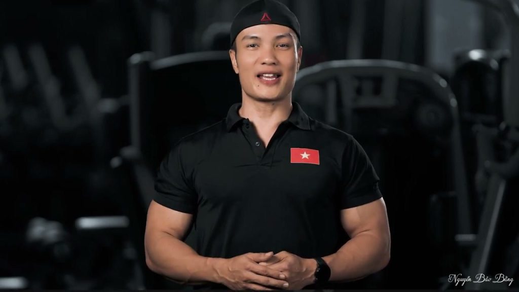 Nguyễn Bảo Bằng mặc áo polo đen, đứng nói trong phòng gym với dàn máy tập phía sau
