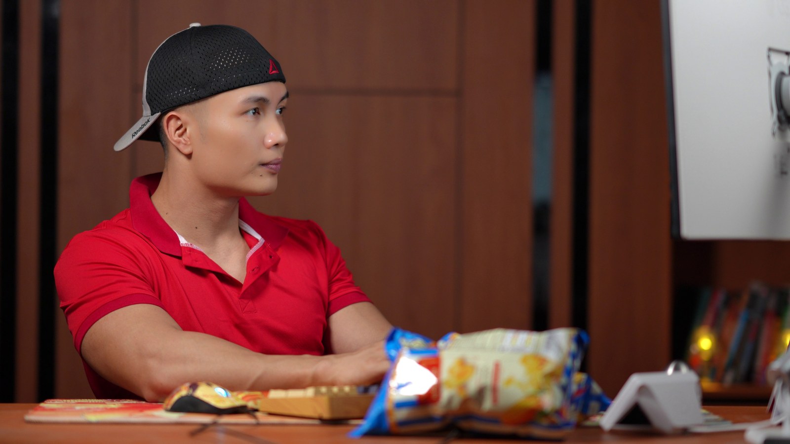Nguyễn Bảo Bằng ngồi làm việc tại bàn, phía trước là bánh snack và đồ ăn vặt