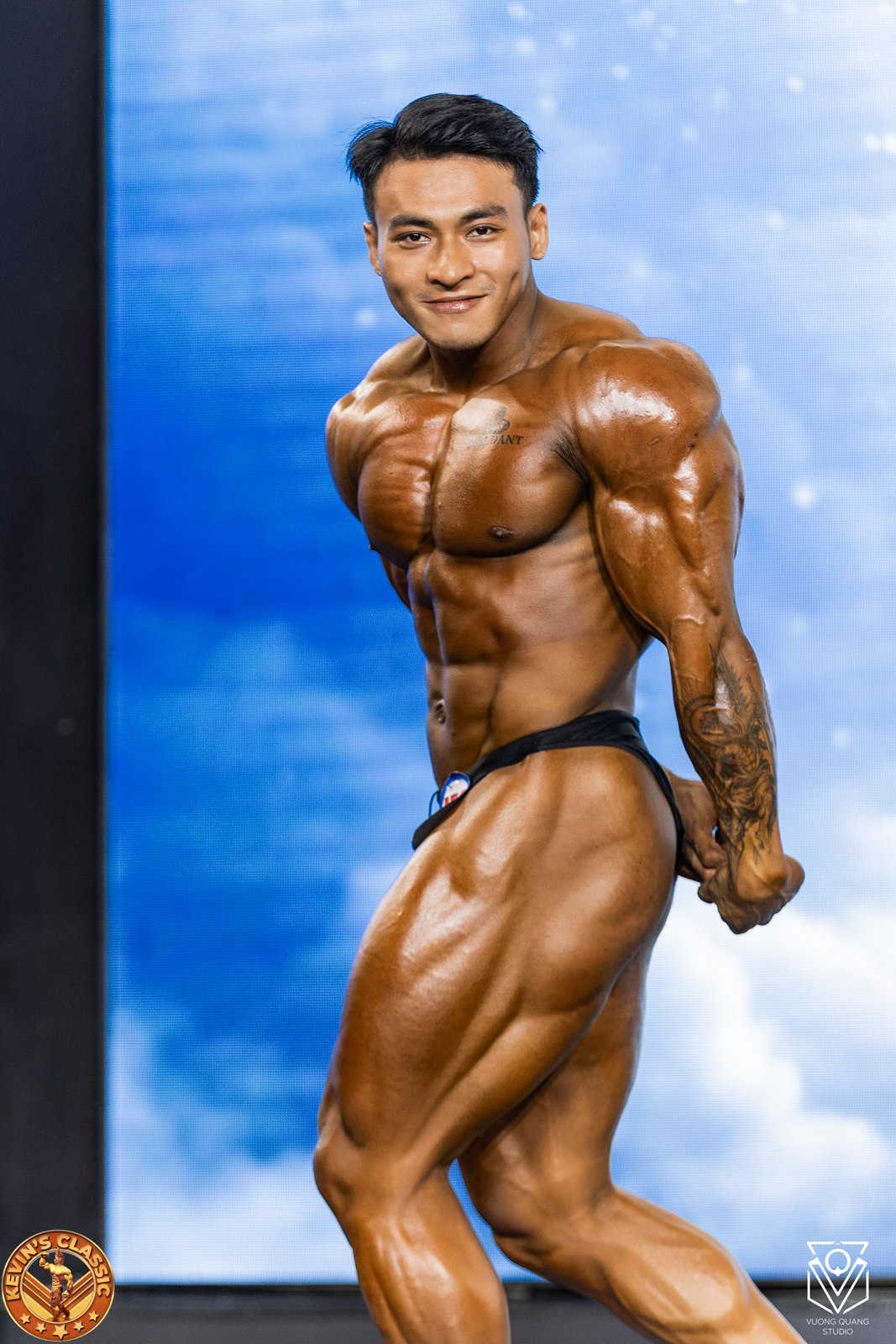 Vận động viên Bodybuilding tạo dáng ngực nghiêng, cơ bắp căng đầy trên sân khấu