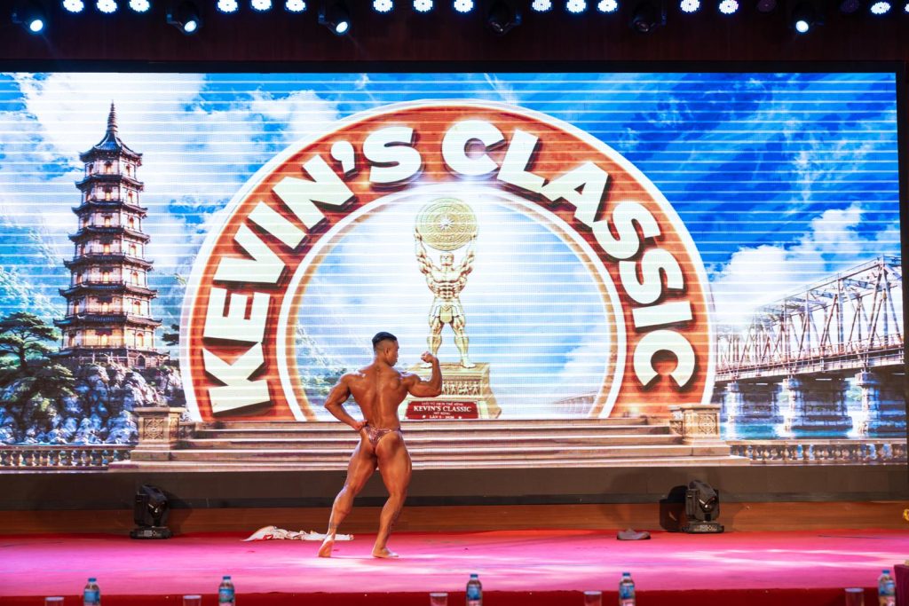 Vận động viên quay lưng tạo dáng trên sân khấu, phía sau là phông Kevin’s Classic