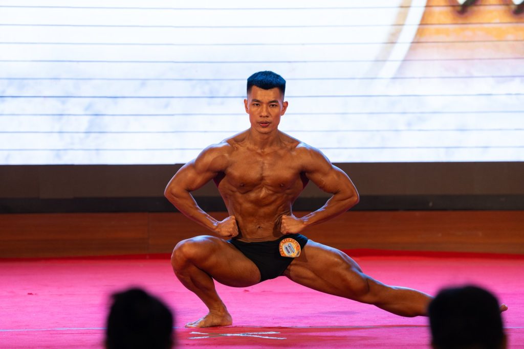 Vận động viên hạ thấp người, một chân duỗi ngang, hai tay chống hông trong bài tự do