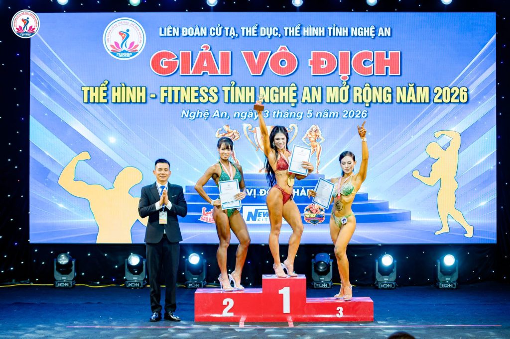 Ông Nguyễn Song Hào, Chủ tịch Liên đoàn Cử tạ, Thể dục, Thể hình tỉnh Nghệ An (trái), cạnh bục 1-2-3 một nội dung nữ – giải thể hình Nghệ An 2026