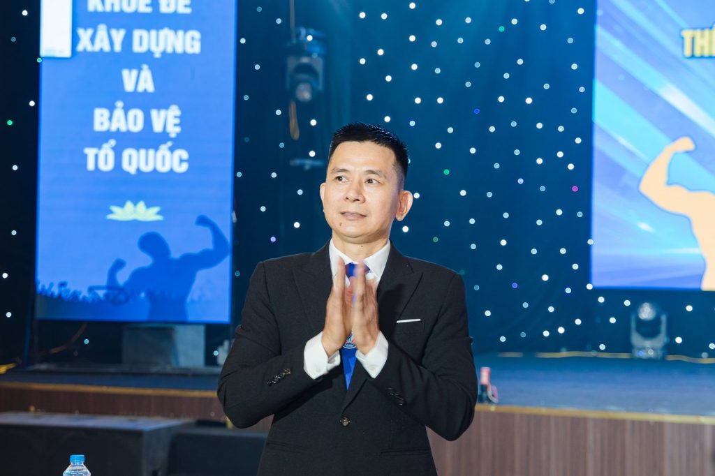 Ông Nguyễn Song Hào, Chủ tịch Liên đoàn Cử tạ, Thể dục, Thể hình tỉnh Nghệ An, chắp tay chào khán phòng – giải thể hình Nghệ An 2026