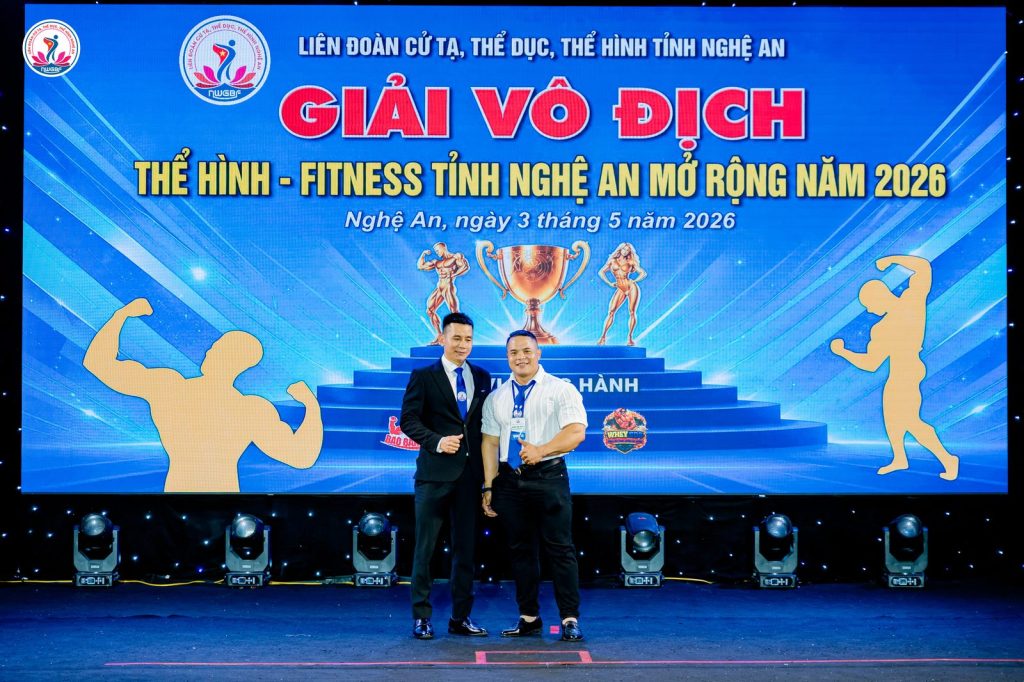 Ông Nguyễn Song Hào, Chủ tịch Liên đoàn Cử tạ, Thể dục, Thể hình tỉnh Nghệ An (trái), chụp ảnh cùng một thành viên tổ trọng tài – giải thể hình Nghệ An 2026
