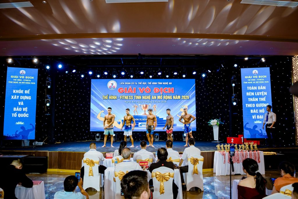 Sân khấu giải thể hình Nghệ An 2026 nhìn từ phía bàn trọng tài, hai băng-rôn dọc hai bên