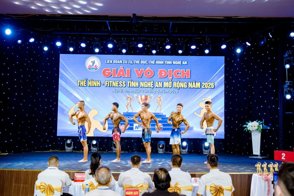 Sân khấu đang so dáng, hàng trọng tài phía trước tại giải thể hình Nghệ An 2026