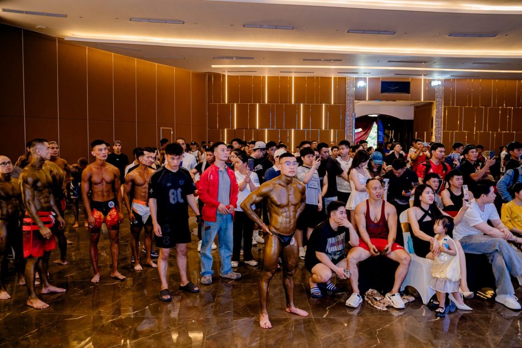 Các vận động viên đã lên màu đứng chờ lượt giữa khán phòng giải thể hình Nghệ An 2026