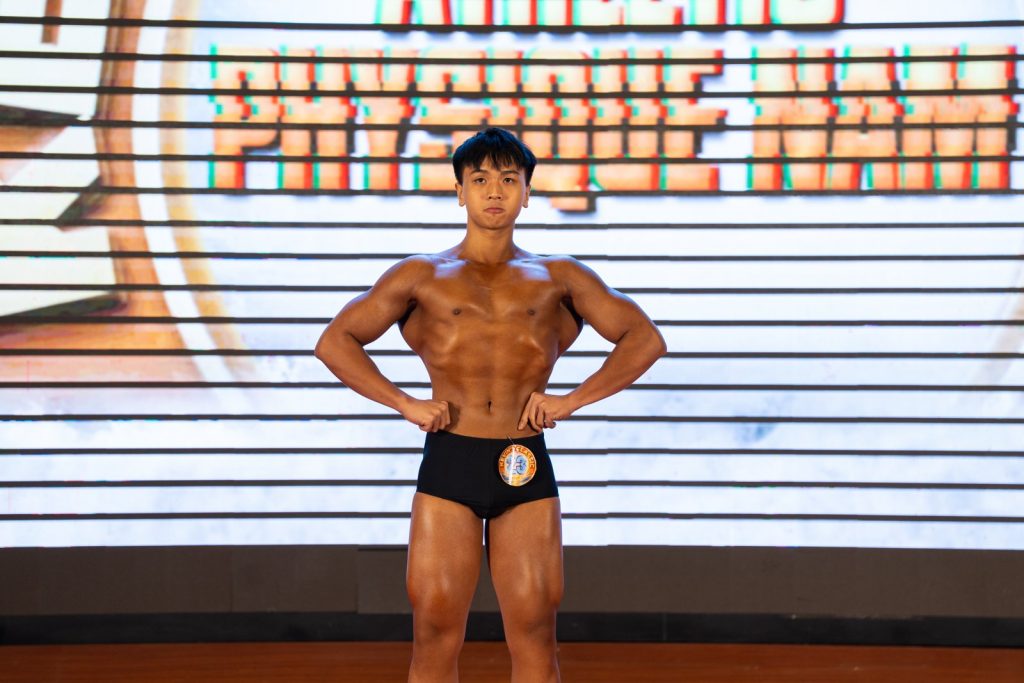 Vận động viên trẻ mở xô trước, phía sau là phông chữ Physique Nam