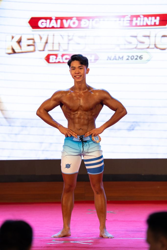 Vận động viên trẻ quần short xanh trắng tạo dáng mặt trước, hai tay chống hông, đứng toàn thân