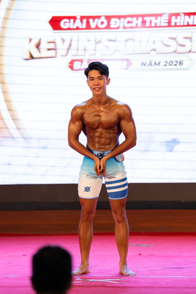 Vận động viên trẻ quần short xanh trắng tạo dáng mặt trước, cười