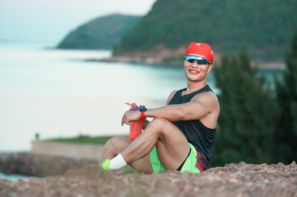 Nguyễn Bảo Bằng cầm bình lắc ngồi nghỉ bên biển
