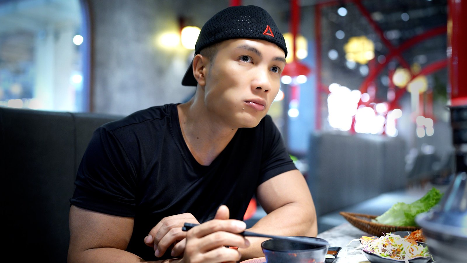 Nguyễn Bảo Bằng ngồi bên bàn ăn có đĩa rau