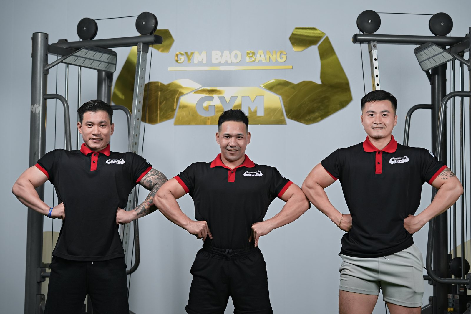 Ba huấn luyện viên cá nhân đứng trong phòng gym