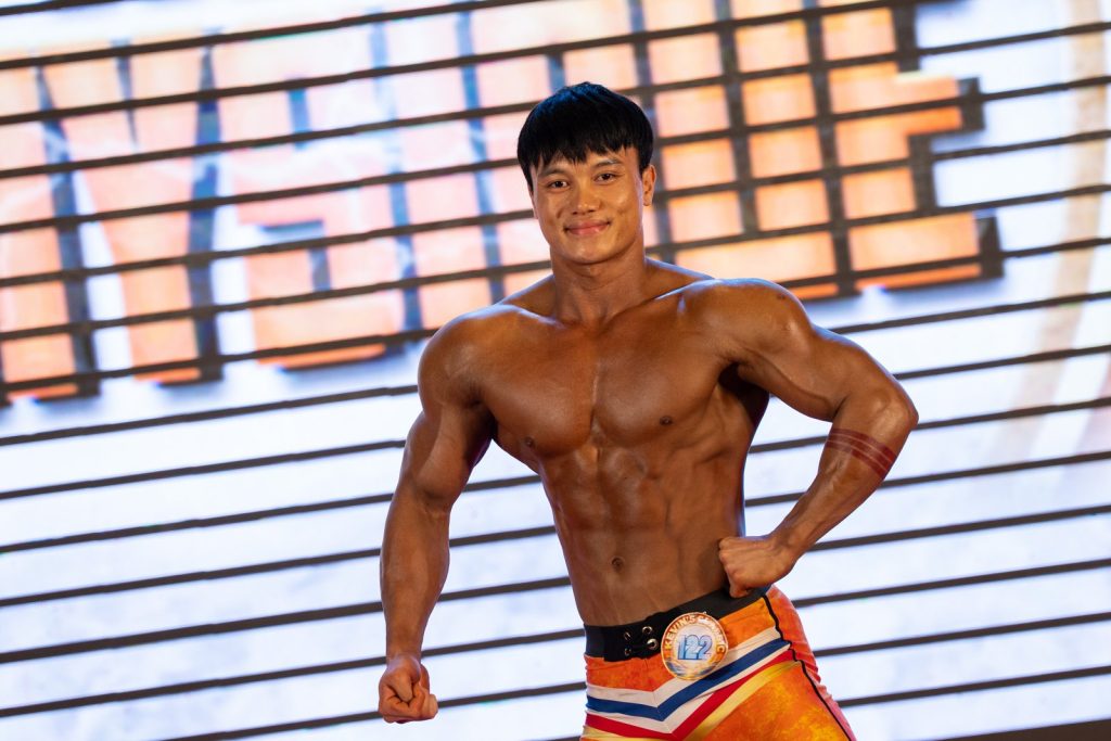 Vận động viên quần short cam tạo dáng mặt trước, một tay chống hông, cười